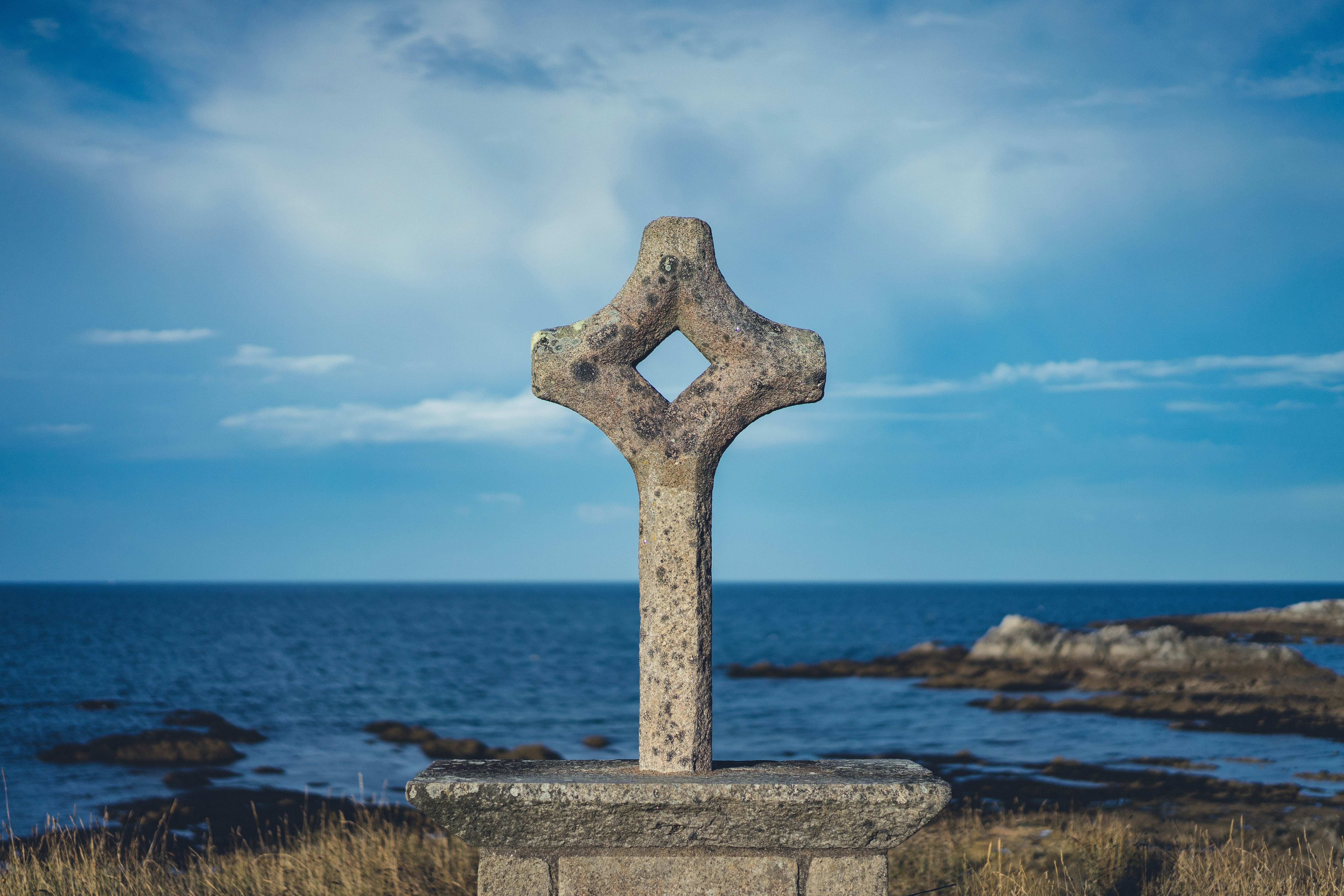 gray concrete cross on gray concrete surface near body of water during daytime